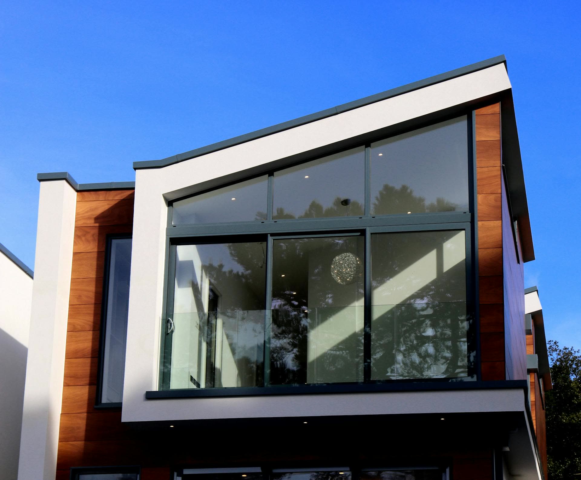 A completed contemporary residence with timber cladding and full-height glazing under a clear sky
