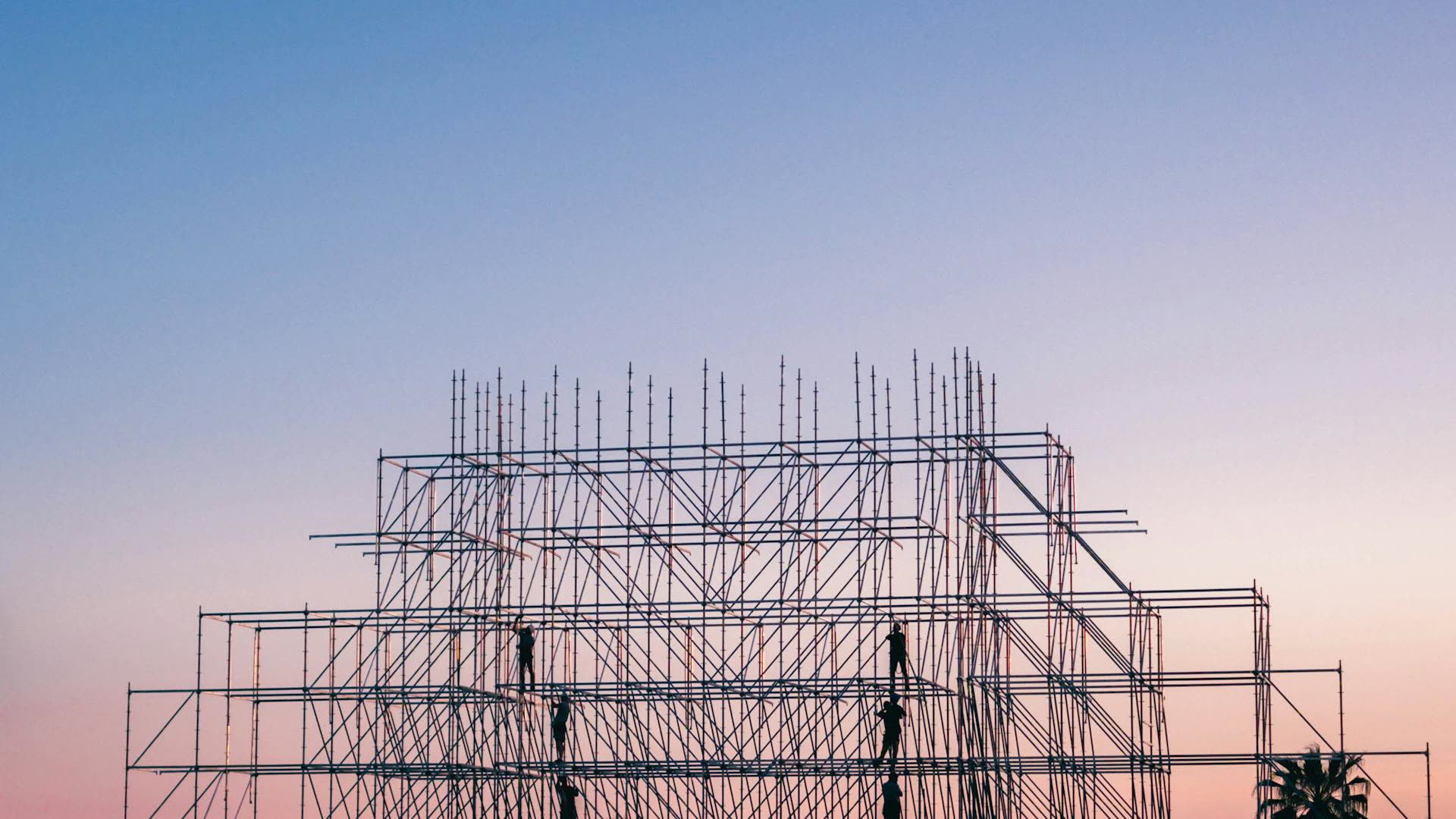 Scaffolding silhouette against a dusk sky on an active construction site