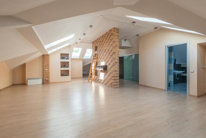 Newly completed loft conversion bedroom with skylights and brick feature wall