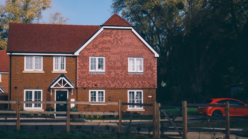 Newly completed brick family home with red roof tiles and timber fencing